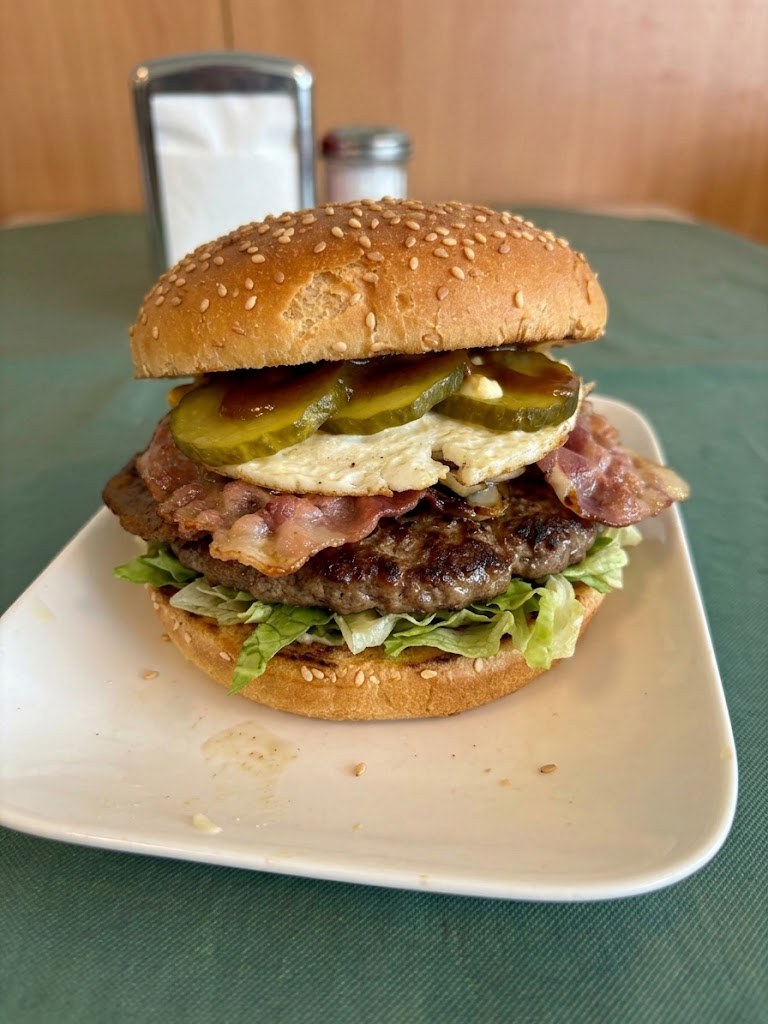D&eacute; Kapteyn burger met bacon, gebakken ei, augurk en sla op een bord